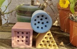 Bunte Ziegel mit Lochstruktur als Bienennisthilfen im Garten vor Pflanzkübeln