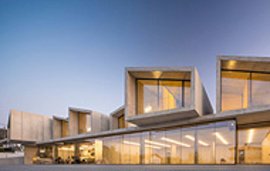 Modernes Gebäude mit Betonfassade und großen Glasflächen bei Dämmerung