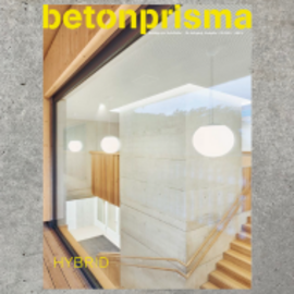Titelbild des Betonprisma-Magazins mit gelbem Titeltext, das einen modernen Innenraum mit einer massiven Betonstütze und einer Holztreppe zeigt.